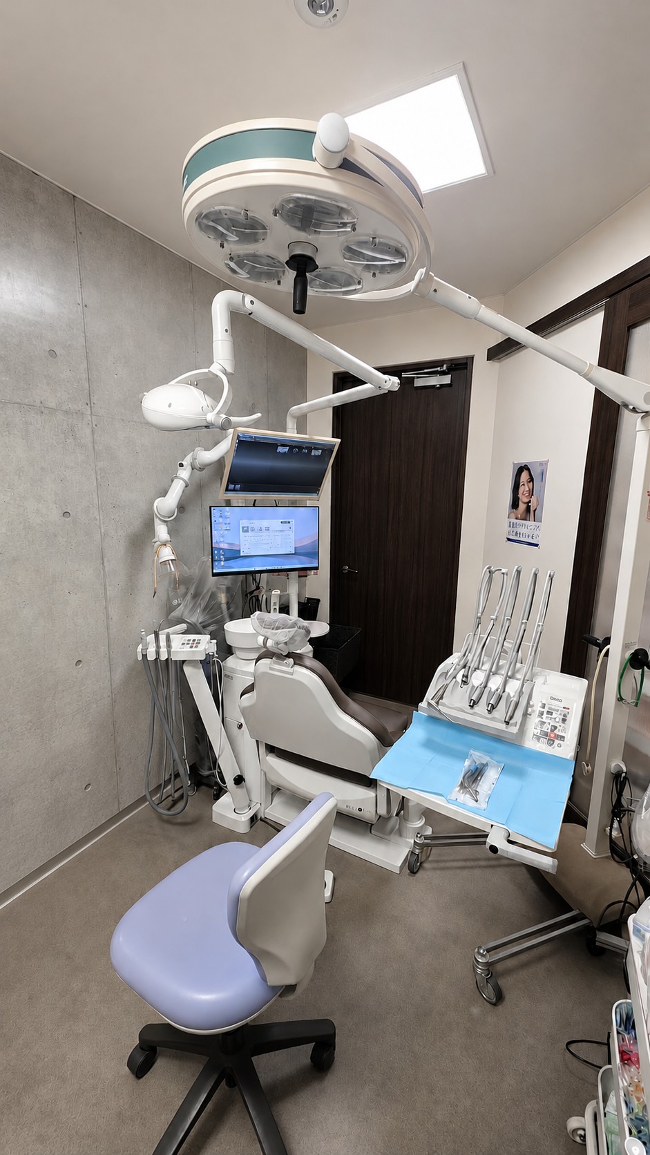 診療チェア、モニター、天井の照明を備えた当院の個室診療室